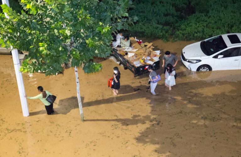 郑州：暴雨过后汽车被淹没仅露车顶 市民蹚齐腰深水前行